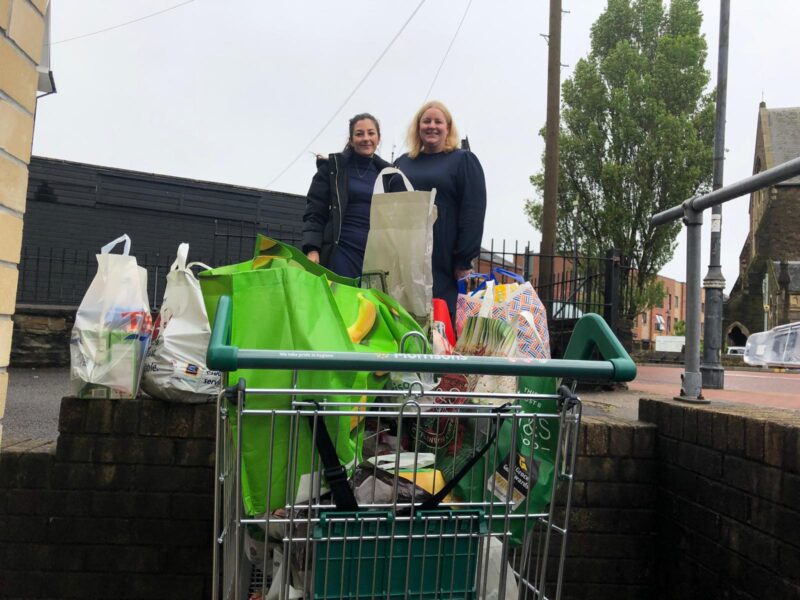 Two staff from Trade Centre Wales with a food donation in a trolley